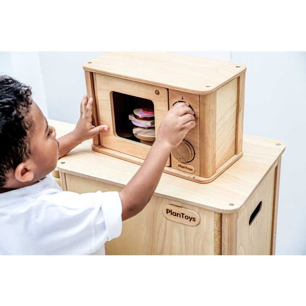 Kid playing PlanToys Microwave