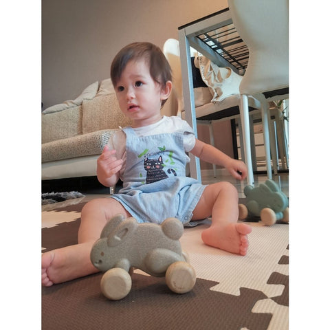 Kid playing PlanToys Push Along Bunny - Grey